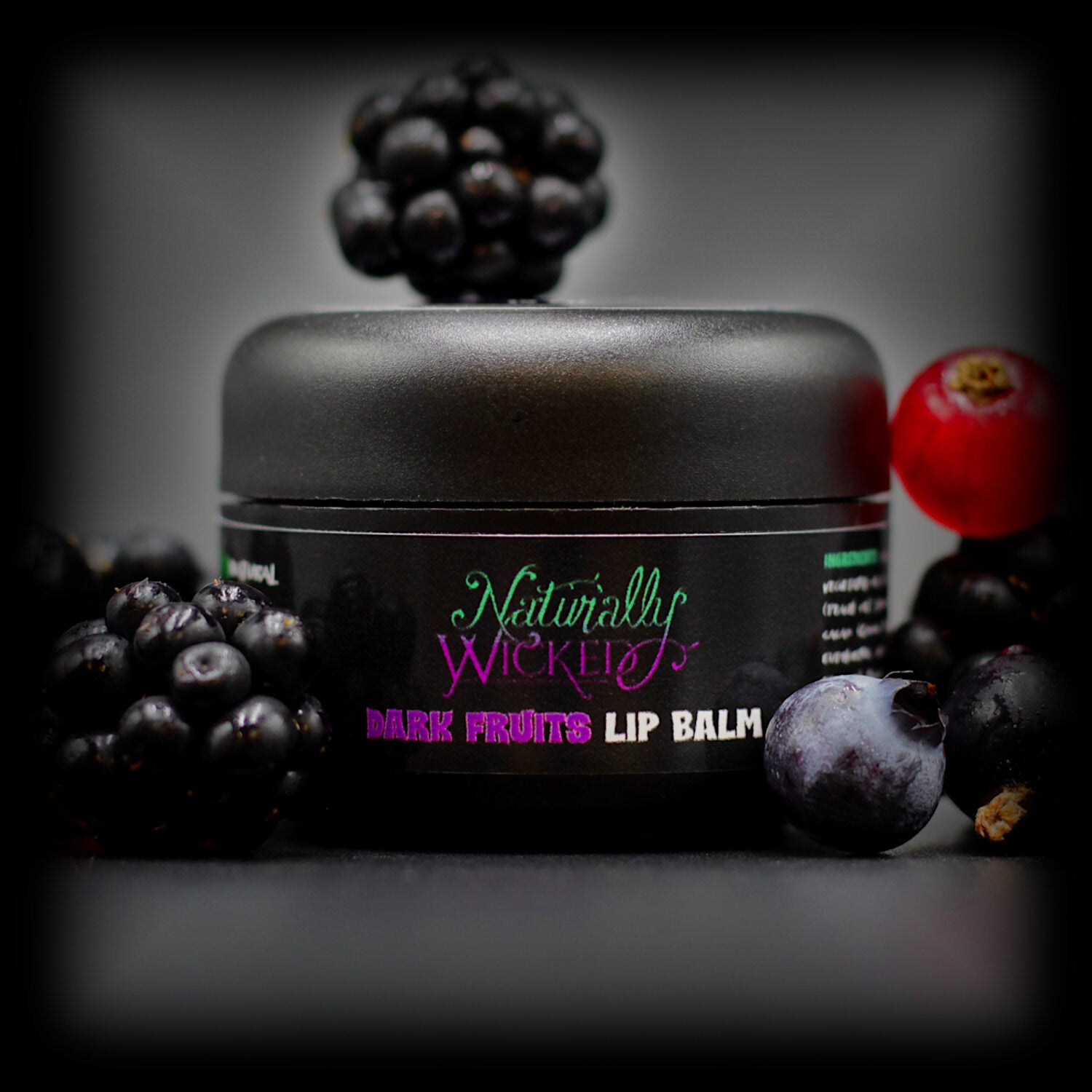 Naturally Wicked Dark Fruits Lip Balm Surrounded By Blueberries, Blackberries & Cranberries