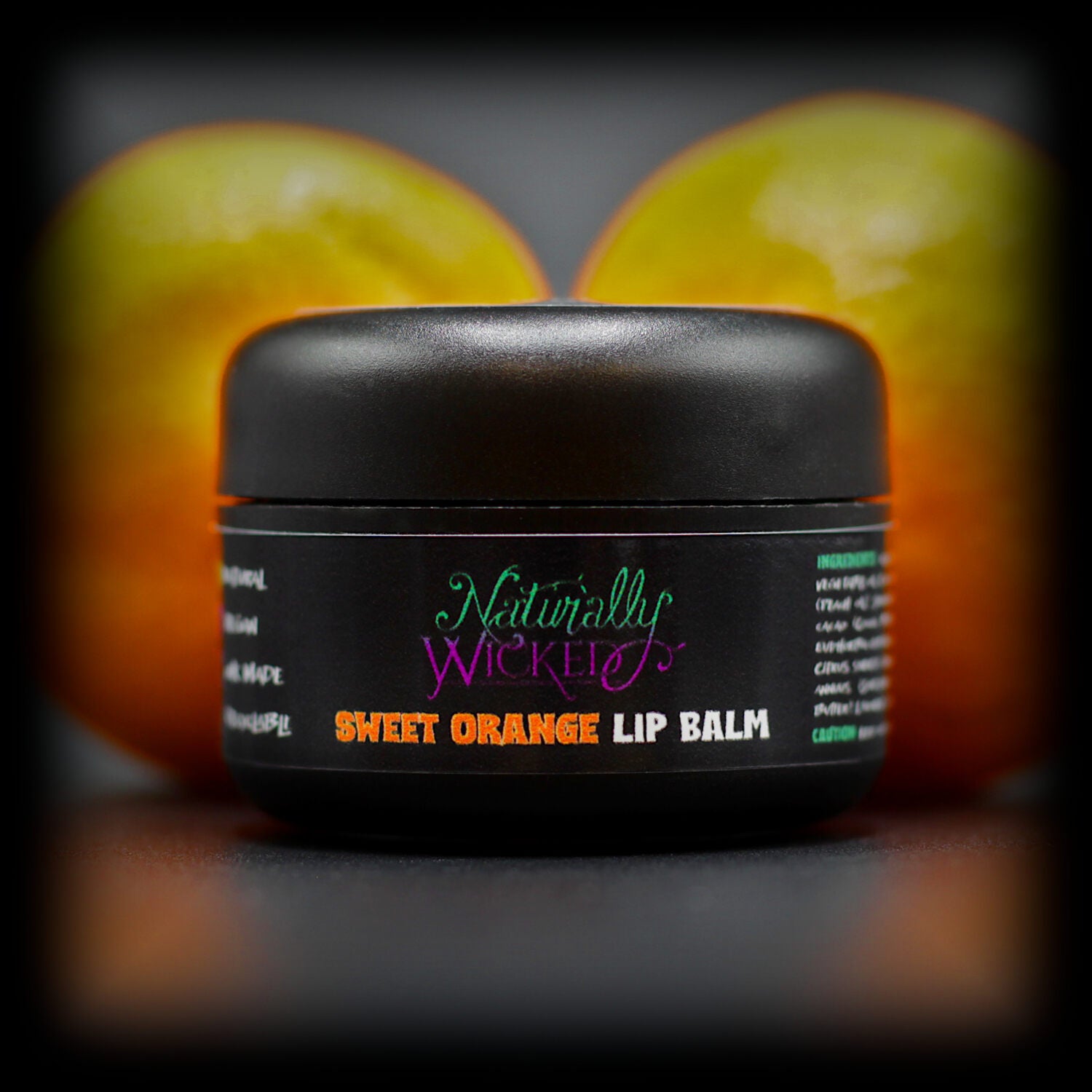 Naturally Wicked Sweet Orange Lip Balm In Front Of Two Juicy Orange Fruits