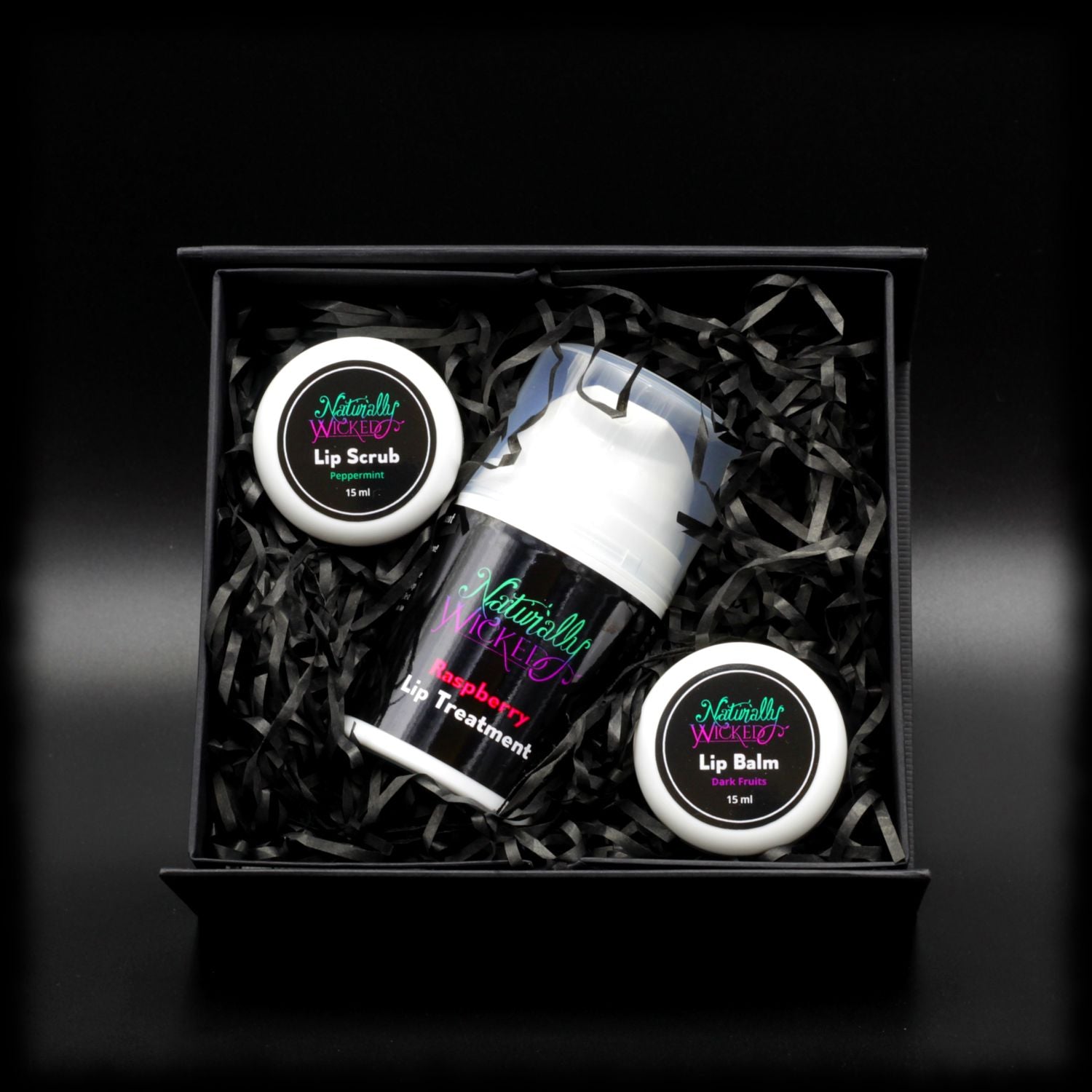 Naturally Wicked Peppermint Lip Scrub, Raspberry Lip Treatment & Dark Fruits Lip Balm Within Black Gift Packaging In Naturally Wicked Original Box
