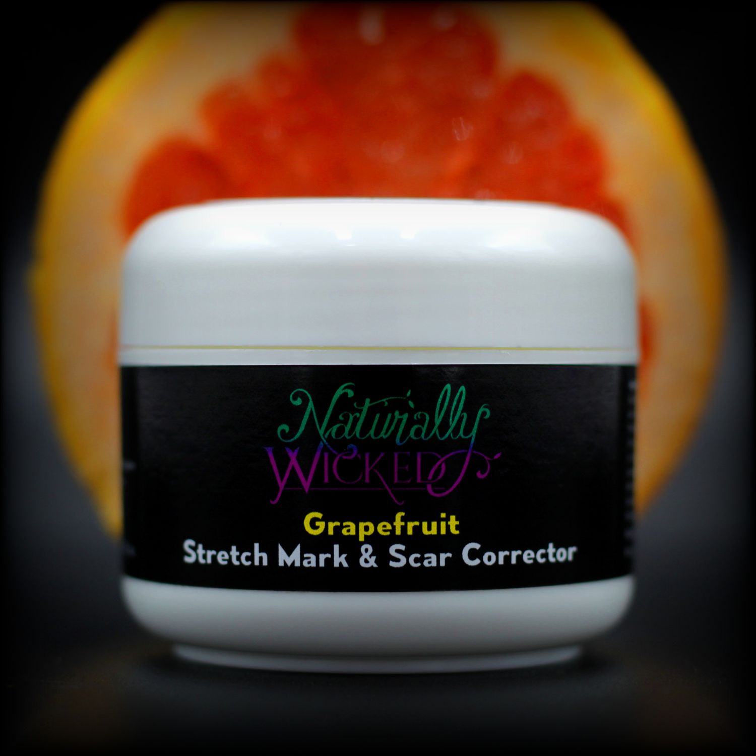 Naturally Wicked Grapefruit Stretch Mark & Scar Corrector In Front Of Red Sliced Grapefruit