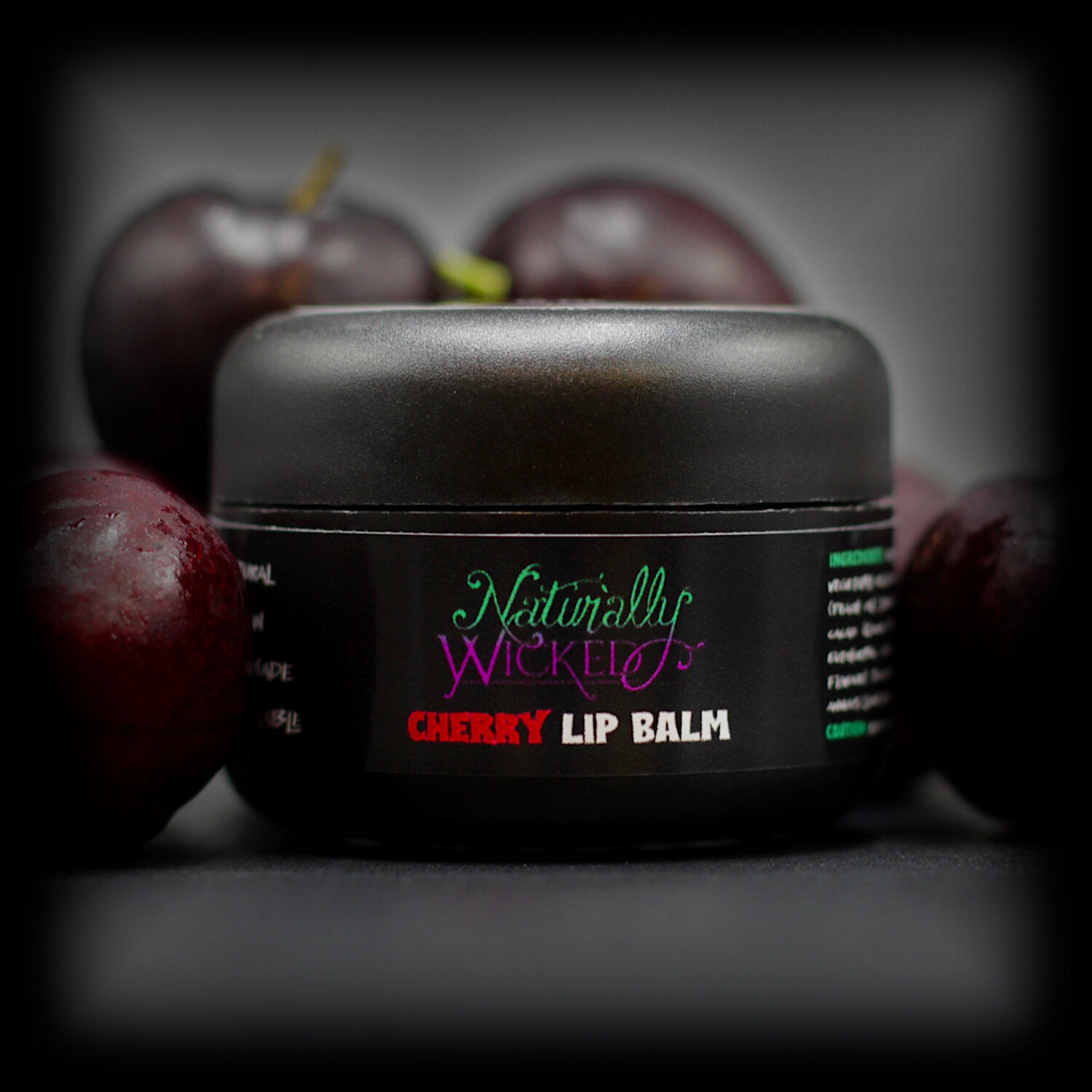 Naturally Wicked Cherry Lip Balm Amongst Dark Crimson Juicy Cherries