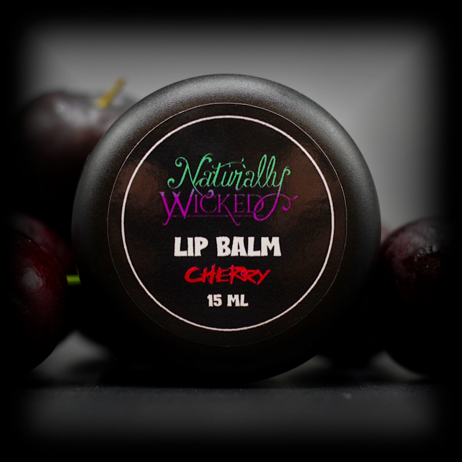 Naturally Wicked Cherry Lip Balm Lid Amongst Sweet Cherries