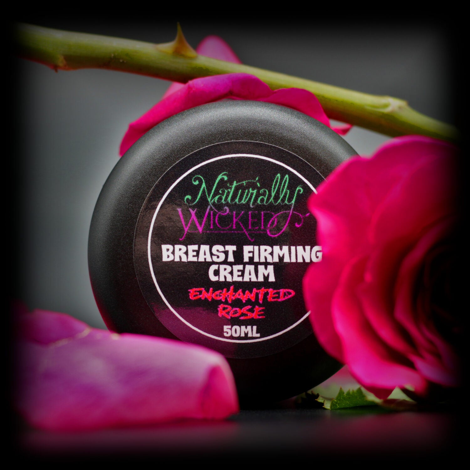 Naturally Wicked Enchanted Rose Breast Firming Cream Vibrant Lid Amongst Pink Roses, Thorny Stem & Petals