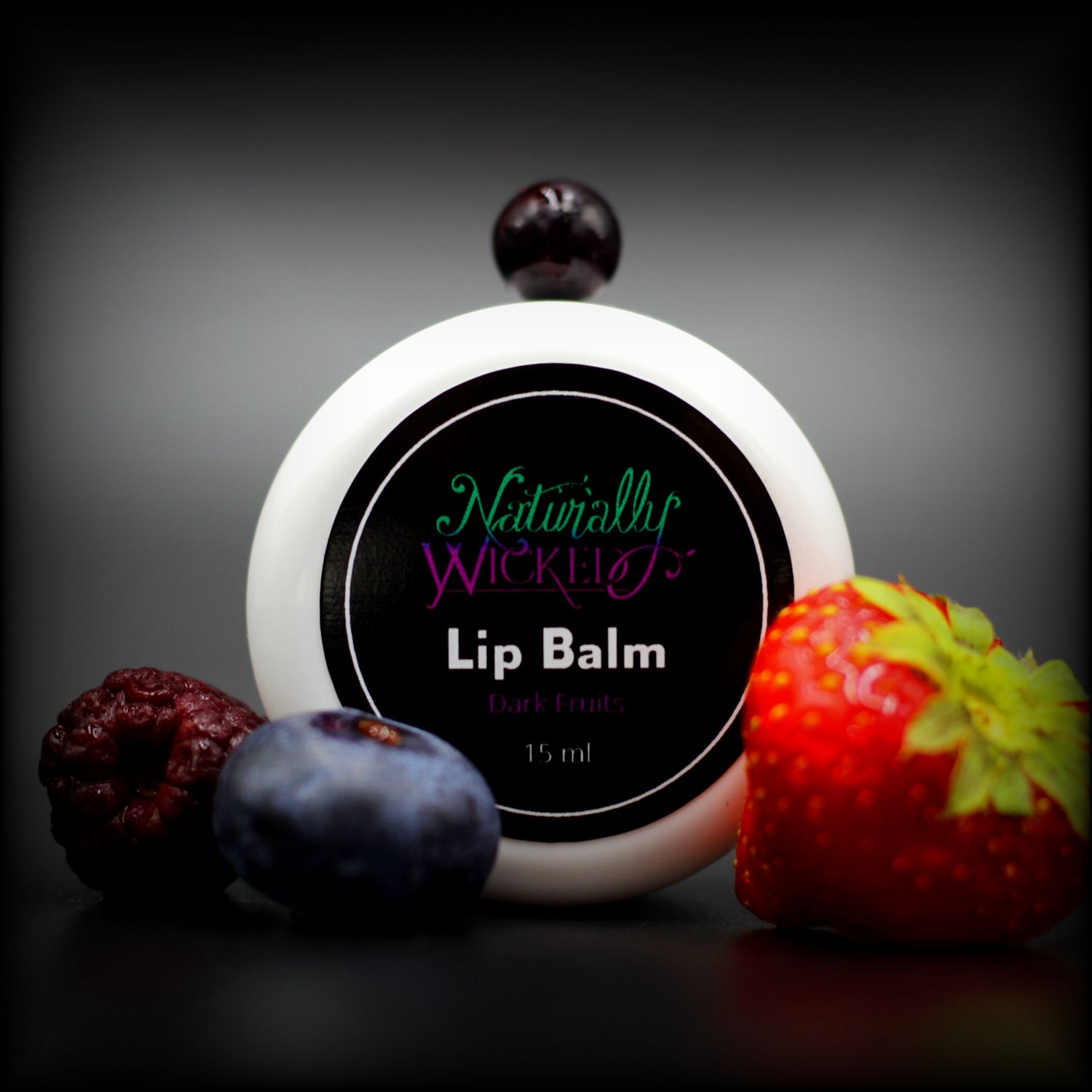 Naturally Wicked Dark Fruits Lip Balm Lid Surronded By Strawberry, Blueberry & Blackberry, with Blackcurrant On Top