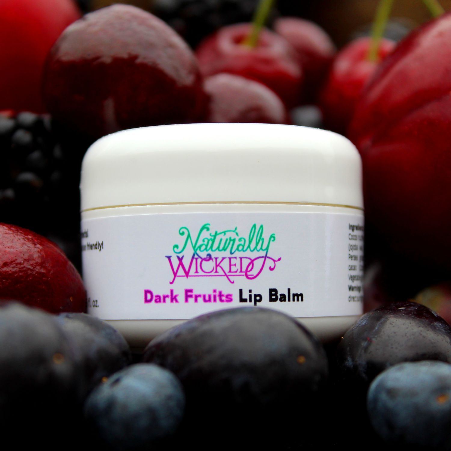 Naturally Wicked Dark Fruits Lip Balm Surrounded By Dark Plums, Blueberries, Blackberries, Cherries & Dark Grapes