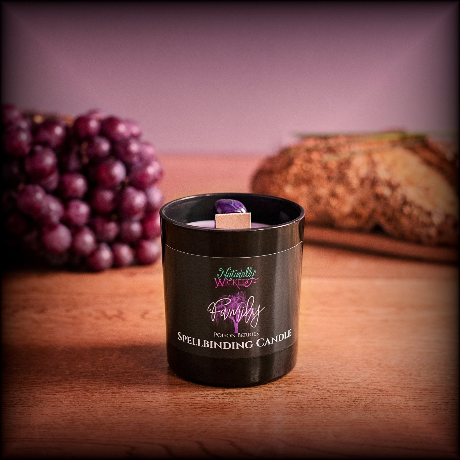 A Scenic View Of The Perfect Spell Candle. Naturally Wicked Spellbinding Family Candle Proudly Presents It's Dark Black Gloss Label With A Poison Berries Purple Family Tree On The Front. The Candle Features Plant-based Smooth Purple Wax, A Wood Wick And A Purple Agate Crystal. Perfect For All The Family