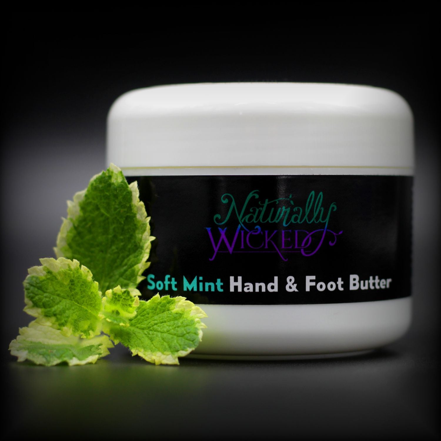 Naturally Wicked Soft Mint Hand & Foot Butter Beside Variegated White & Green Mint Leaves