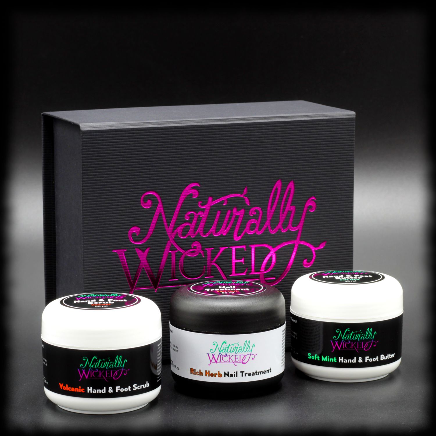 Naturally Wicked Original 3 Step Hand & Foot Kit With Volcanic Hand & Foot Scrub, Rich Herb Nail Treatment & Soft Mint Hand & Foot Butter In Front Of Original Black & Pink Box