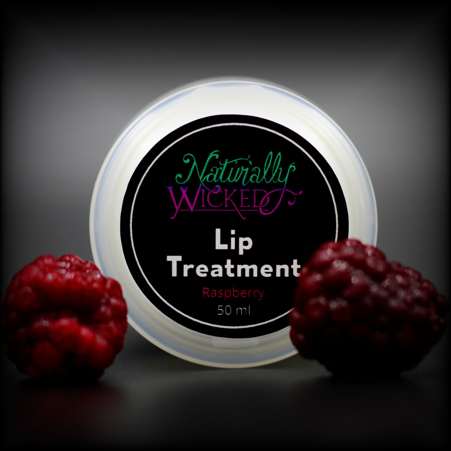 Naturally Wicked Raspberry Lip Treatment Lid With Two Bright Red Raspberries In Front