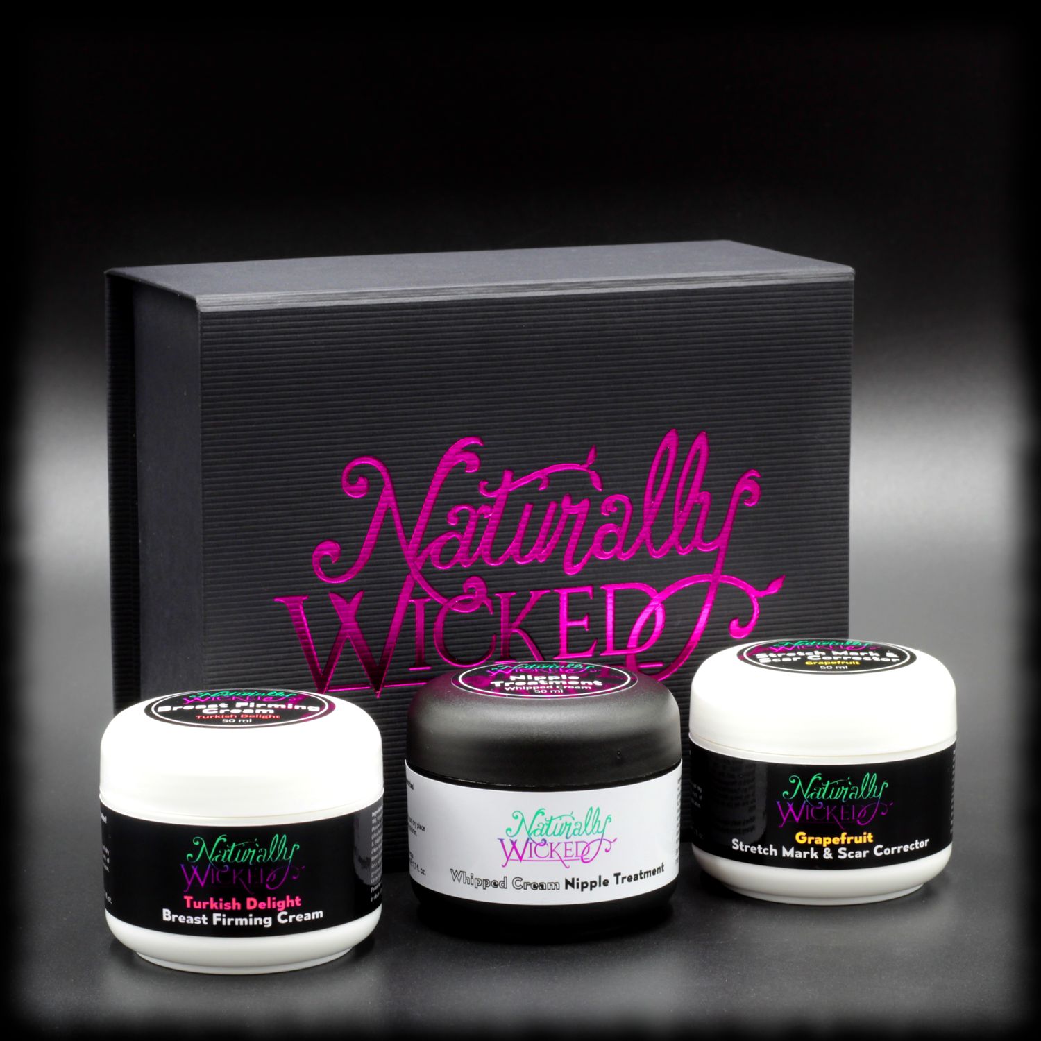 Naturally Wicked Original 3 Step Mamma Kit With Turkish Delight Breast Firming Cream, Whipped Cream Nipple Treatment & Grapefruit Stretch Mark & Scar Corrector In Front Of Black & Pink Naturally Wicked Original Box