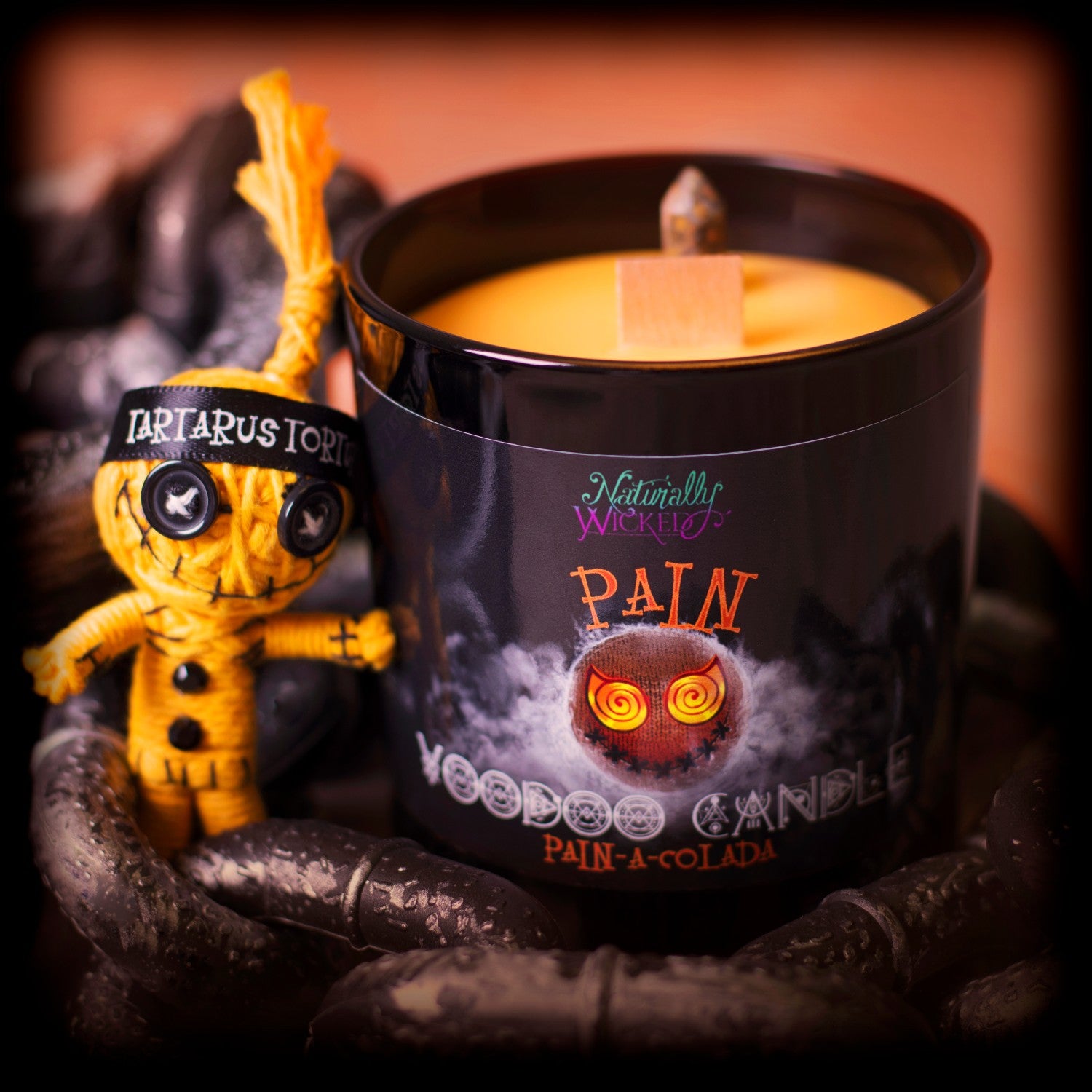Naturally Wicked Voodoo Pain Spell Candle Entombed With Orange Crystal Beside Orange Pain Voodoo Doll