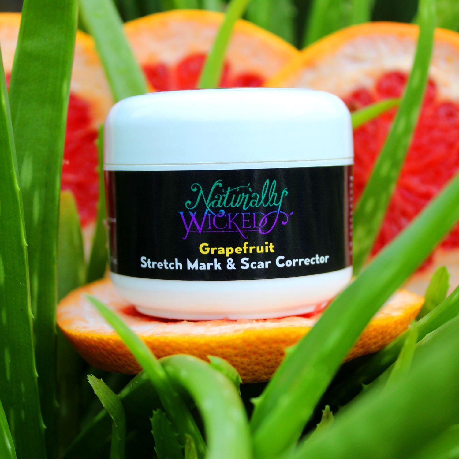 Naturally Wicked Stretch Mark & Scar Corrector Sat In Green Aloe Vera On Top Of Bright Pink Grapefruit With Orange Skin