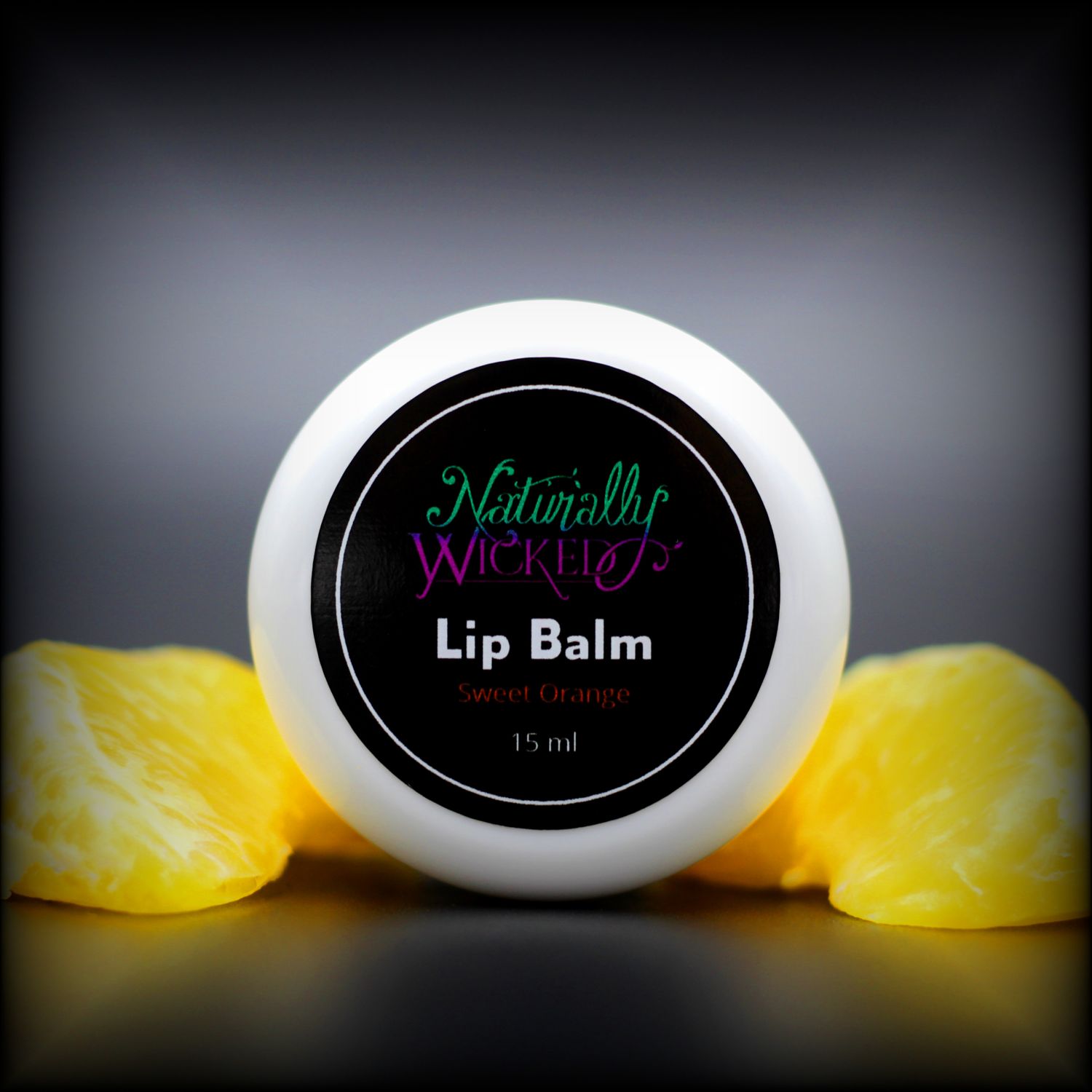 Naturally Wicked Sweet Orange Lip Balm Lid With Orange Fruit Segments Lay Either Side